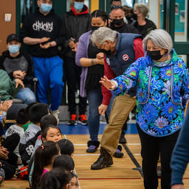La gouverneure générale salue des étudiants alors qu'elle entre dans un gymnase.