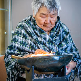 A woman has a bowl of fire in front of her.