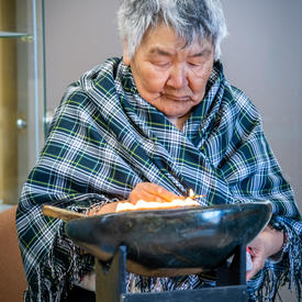 Une femme a un bol de feu devant elle.