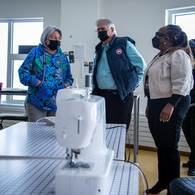 Leurs Excellences font une visite guidée. On aperçoit une machine à coudre au premier plan.