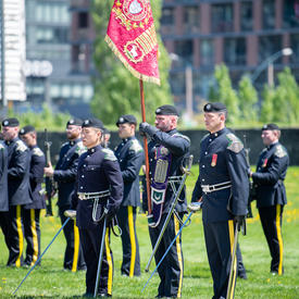 A member of the Queen’s York Rangers is holding the new flag.