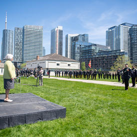 The Governor General in standing on a small outdoor platform facing the Queen's York Rangers.
