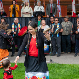 A woman is holding a little girl’s hand during a performance.