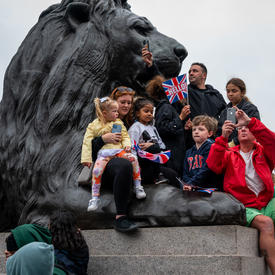 Children and adults are perched atop a large statue of a lion.