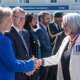 The Governor General is shaking hands with people upon her arrival in the Yukon.