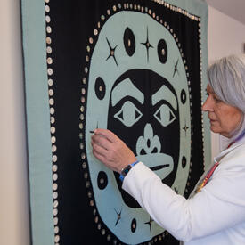 La gouverneure générale Simon admire une œuvre d’art autochtone accrochée au mur.