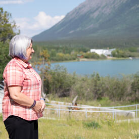 La gouverneure générale Simon est debout à l'extérieur. Elle regarde le lac et la montagne en face d'elle.
