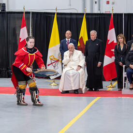 Des musiciens vêtus de vêtements traditionnels inuits se produisent. La gouverneure générale Simon, le pape François et plusieurs autres personnes regardent.
