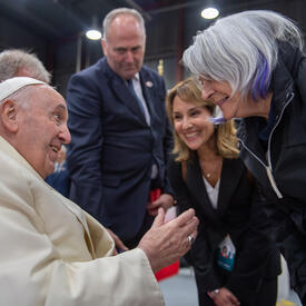Pope Francis and Governor General Simon face each other. They are talking and smiling. There are people around them.