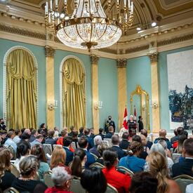 The Governor General is standing at a podium in the ballroom at Rideau Hall.