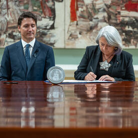 Le Premier ministre Justin Trudeau et la gouverneure générale Mary Simon sont assis à une grande table en bois.
