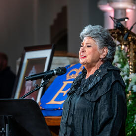 A woman is singing as part of the memorial service.