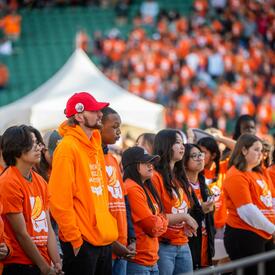 Une foule de personnes portant des chandails orange dans un stade.