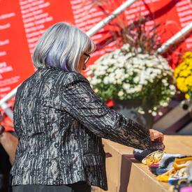 Governor General Mary Simon placing a pair of shoes on a stage.
