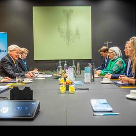 La gouverneure générale Mary Simon et M. Ólafur Ragnar Grímsson sont assis en face l'un de l'autre à une longue table. Plusieurs autres personnes sont assises à la table. Ils sont en train de discuter. 