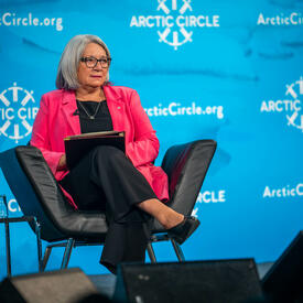 La gouverneure générale Simon est assise dans un fauteuil noir sur la scène. Sur l'écran derrière elle, on peut lire « Arctic Circle ».