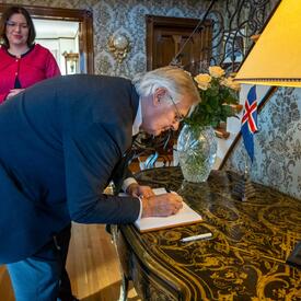 M. Fraser signe un livre des visiteurs.