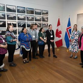 La gouverneure générale et un petit groupe de personnes se tiennent ensemble dans une salle. Un drapeau du Canada et un drapeau de l'Islande sont en arrière-plan.