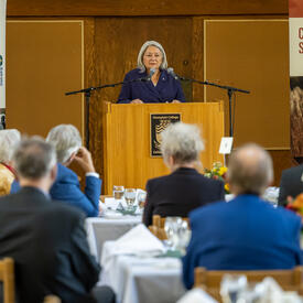 View from the audience of the Governor General speaking from a podium.