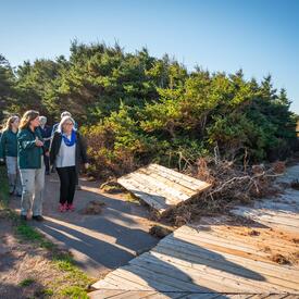 La gouverneure générale est debout avec un petit groupe de personnes regardant les dégâts causés par l'ouragan Fiona.