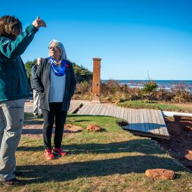 La gouverneure générale écoute une dame portant une veste verte. Elles sont debout à l'extérieur.