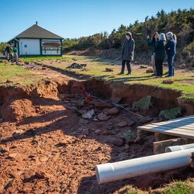 La gouverneure générale est debout avec un groupe de personnes regardant les dégâts causés par l'ouragan Fiona.