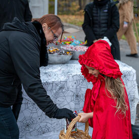 Un jeune enfant portant un bonnet rouge reçoit des friandises d'Halloween.