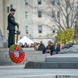 Une couronne de fleurs en l'honneur de la reine Elizabeth II se trouve près de la Tombe du Soldat inconnu à Ottawa. Une sentinelle monte la garde.