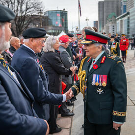 Governor General Mary Simon is shaking hands with a veteran. She is wearing the Canadian Army uniform. 