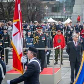 Governor General Mary Simon is saluting. She is wearing the Canadian Army uniform. There is a crowd behind her.