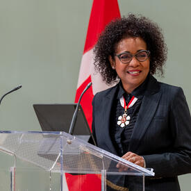 The Right Honourable Michaëlle Jean is standing at a podium in the ballroom at Rideau Hall.