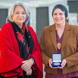 Natasha Camacho is standing next to the Governor General.