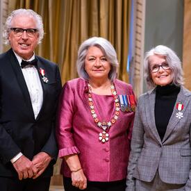 Governor General Simon is standing between a man and a woman who have medals pinned to their blazers.