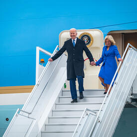 Le président Joe Biden et la première dame Jill Biden sortent d'un l'avion et descendent les escaliers.