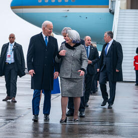Governor General Simon walks next to U.S President Joe Biden. There is a group of people behind them.