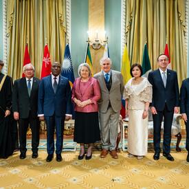 A group photo featuring Governor General Simon and six new heads of mission. Behind them are the flags of each country.