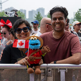 Canada Day crowd goers holding a Cookie monster doll with a Canadian Flag