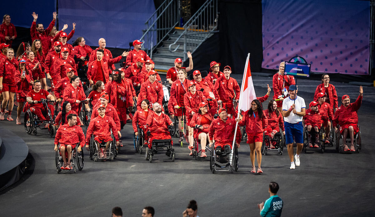 Two flag bearers, Katarina Roxon and Pat Anderson, lead the Canadian team during the opening ceremony of the Paralympic Games in Paris, France. The team proudly marches forward with their flags.