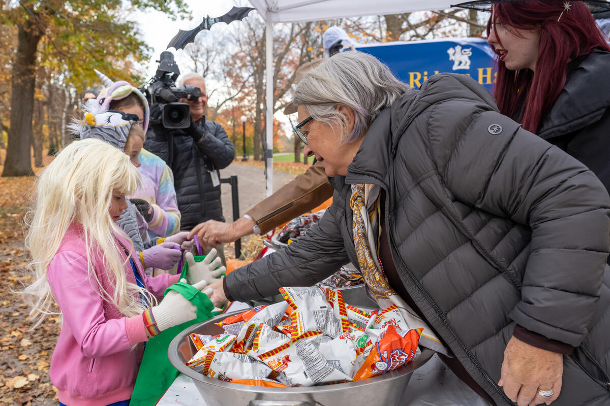 Governor General Mary Simon hands candy out to a child in costume