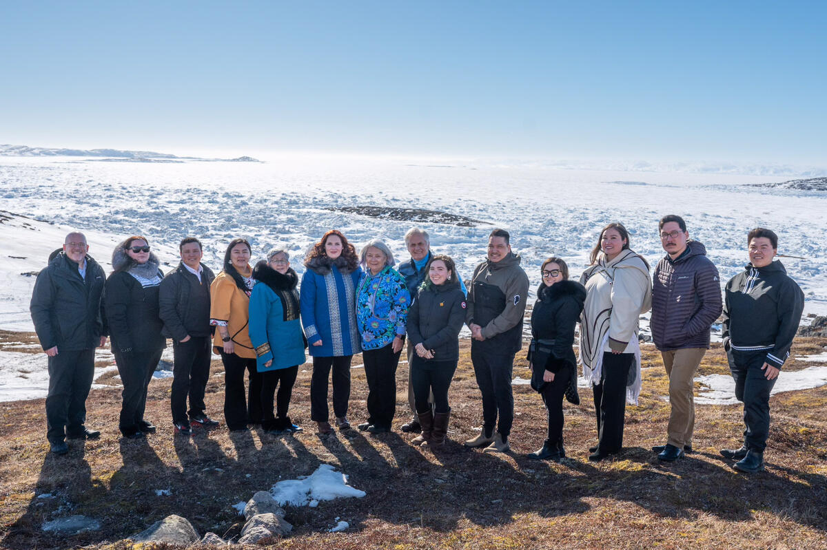 La gouverneure générale Mary Simon se tient au sommet d'une colline enneigée avec des gardiens du savoir et des membres du personnel d'Ilitaqsiniq pour une photo de groupe.