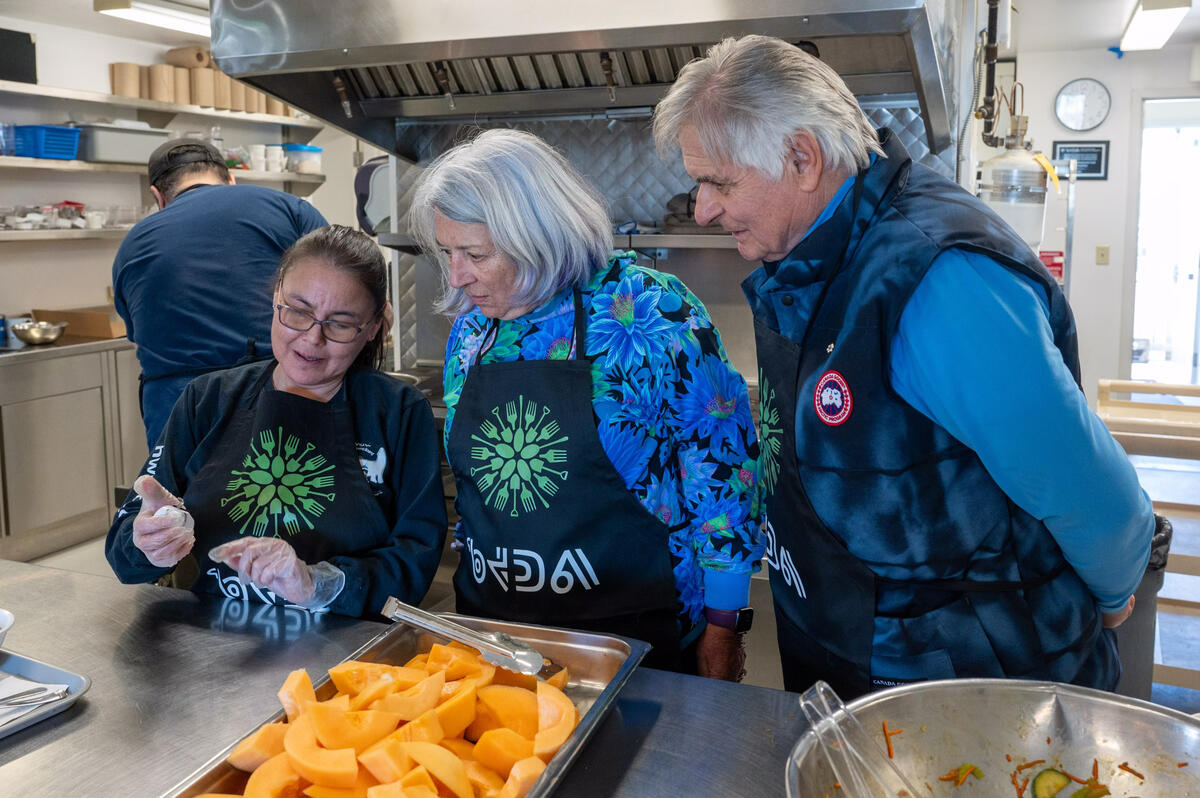 Governor General Mary Simon listens to a member the Qajuqturvik Community Food Centre as they prepare food.