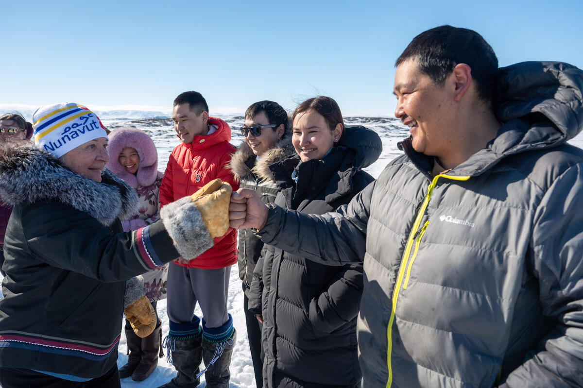 La gouverneure générale Mary Simon donne un coup de poing à un jeune Inuit à l'extérieur dans le cadre de la séance de partage de connaissances avec les jeunes sur les changements climatiques