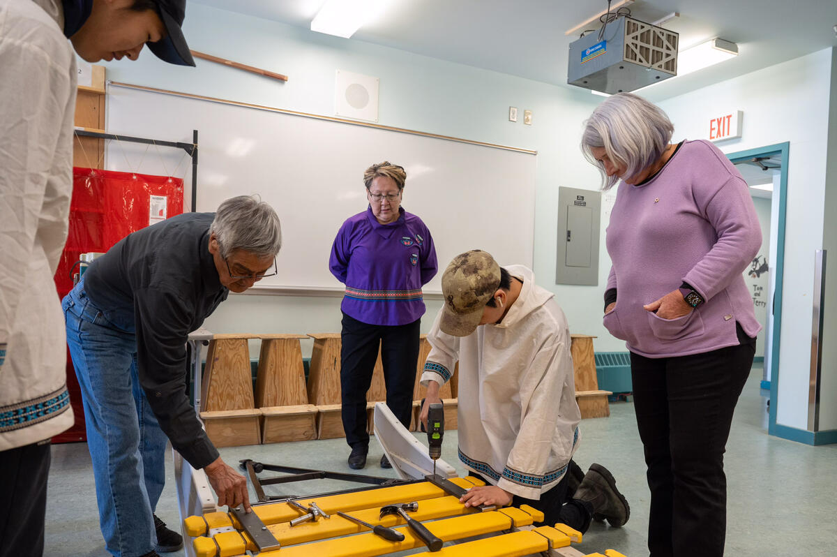 Governor General Mary Simon watches as a student uses a drill on a sled