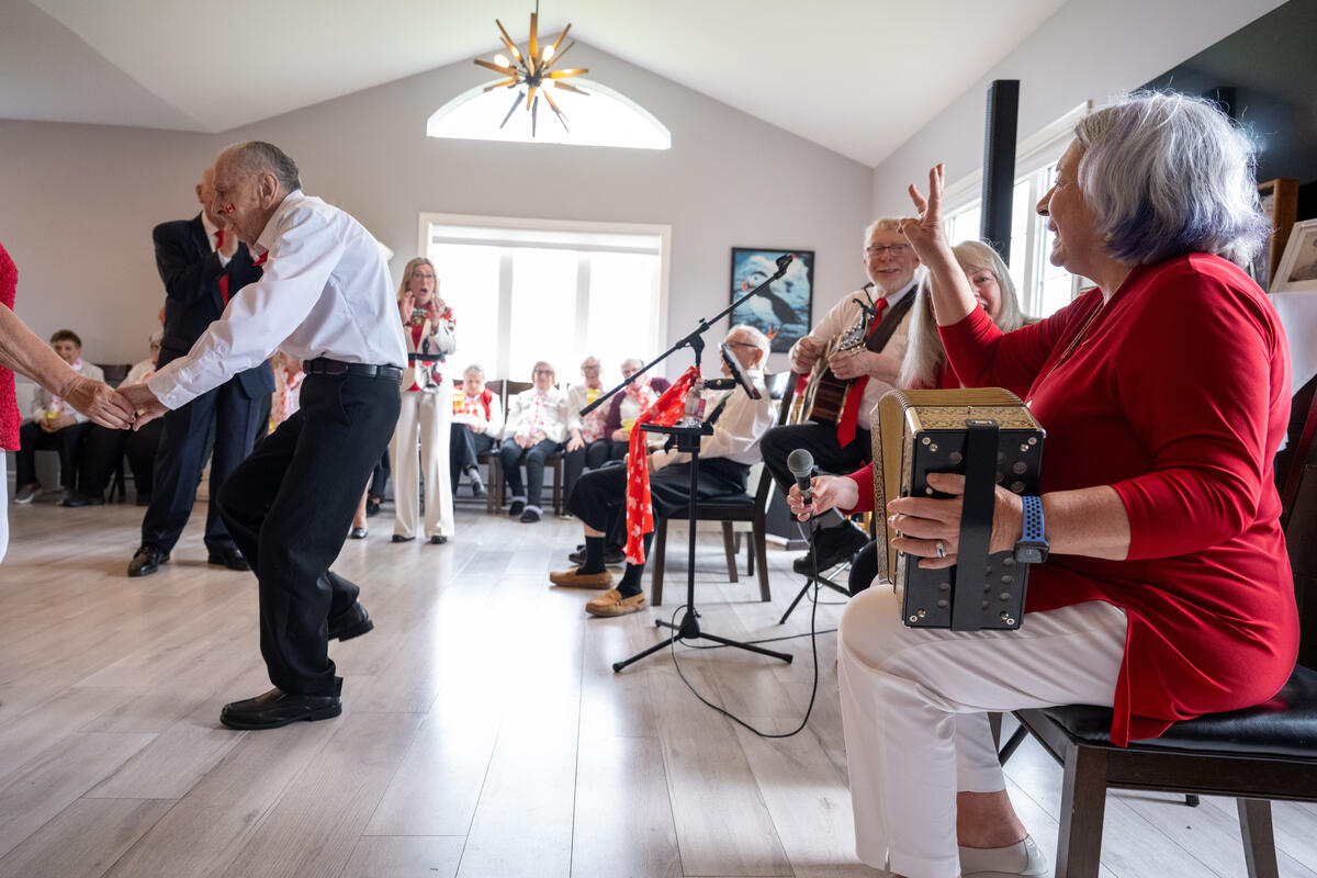 Un orchestre joue lors d'une célébration de la fête du Canada dans une maison de retraite. Les gens dansent. La gouverneure générale Simon joue de l'accordéon.