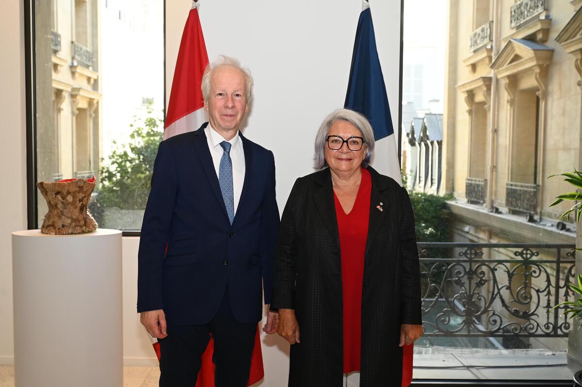 The Governor General Mary Simon stands next to Canada’s Ambassador to France, Stéphane Dion. They are both smiling.