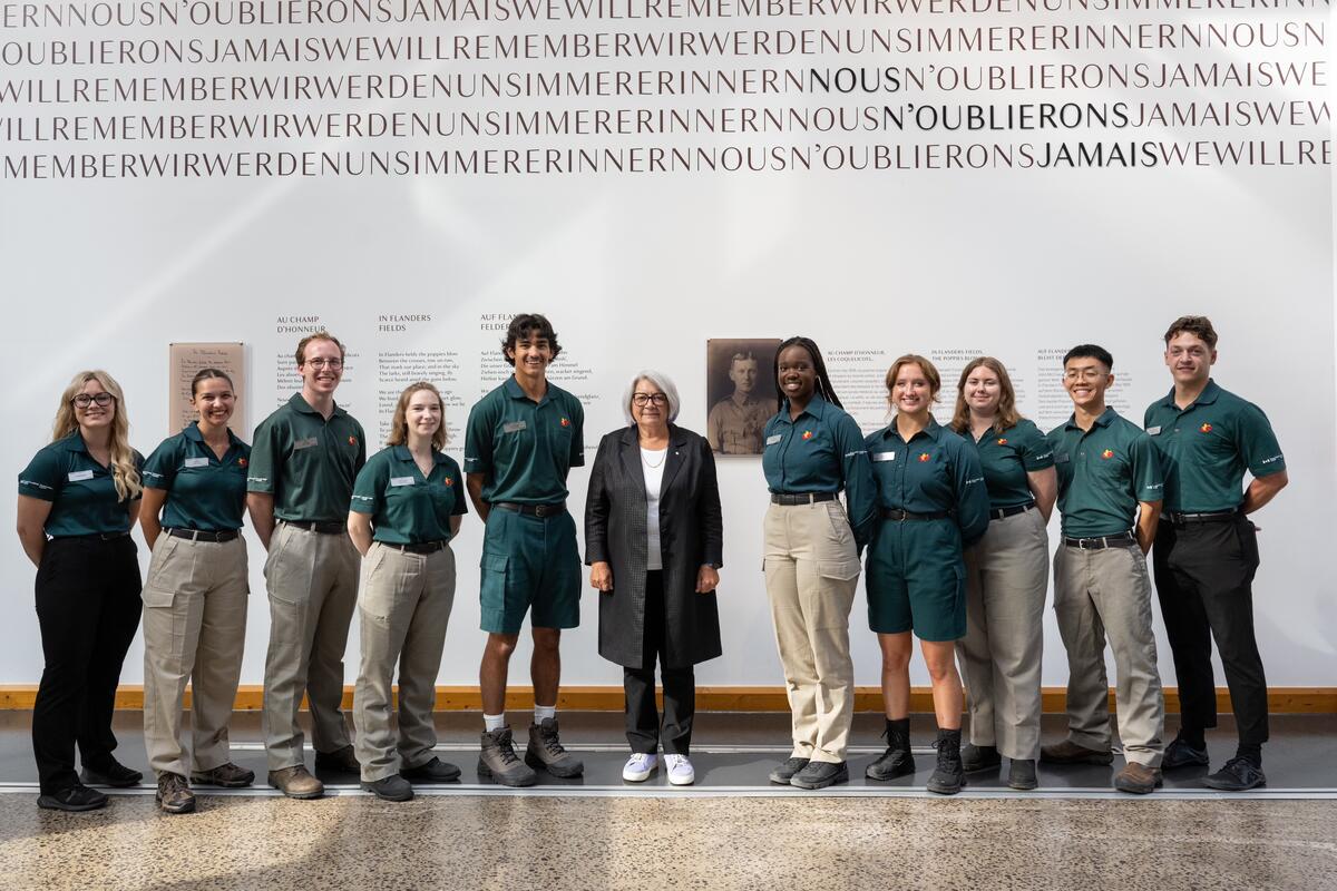 La Gouverneure générale du Canada, Mary Simon, est alignée avec un groupe de personnes devant un mur portant un texte en français.