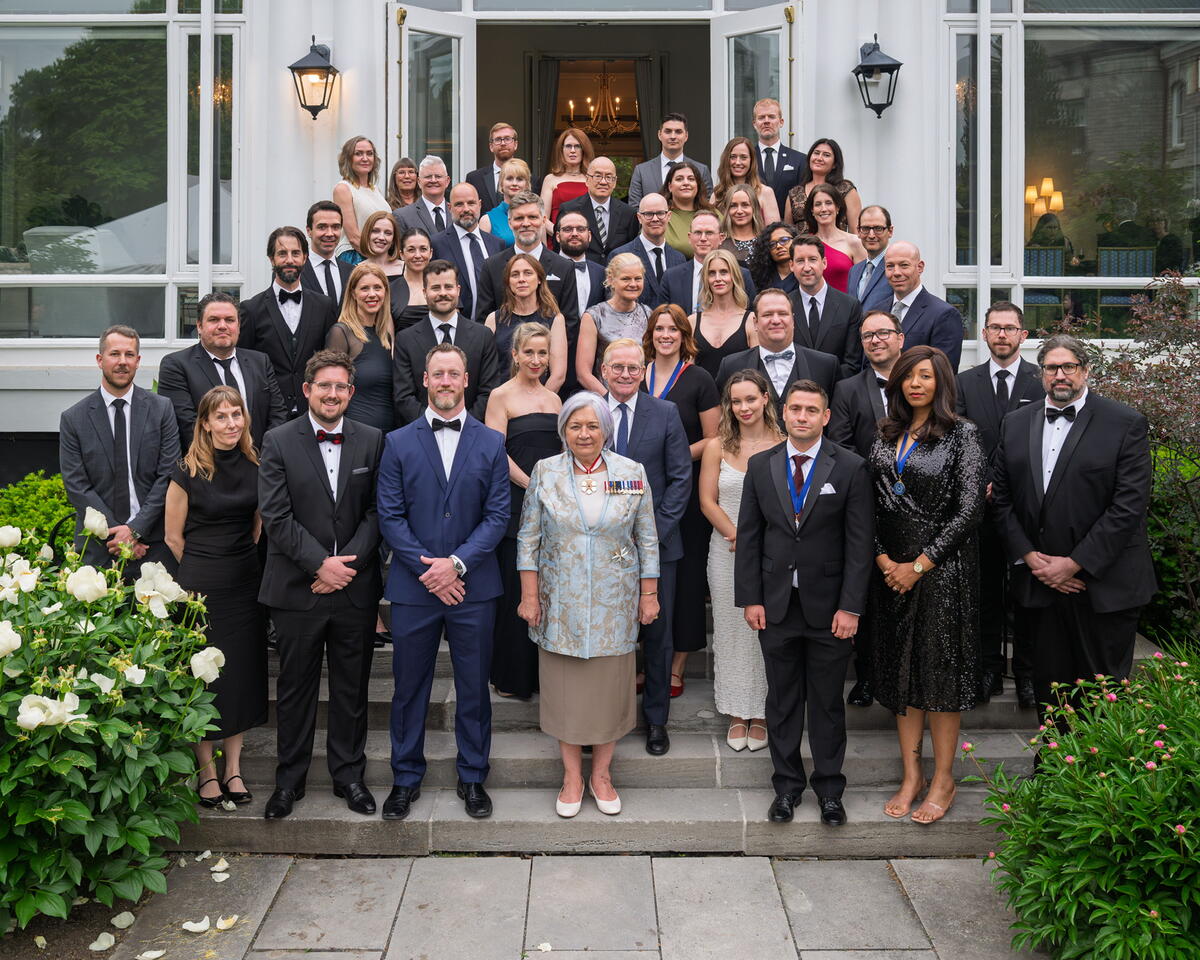 A group of people posing for a photo outside. Governor General Mary Simon is standing in the first row, in the middle.
