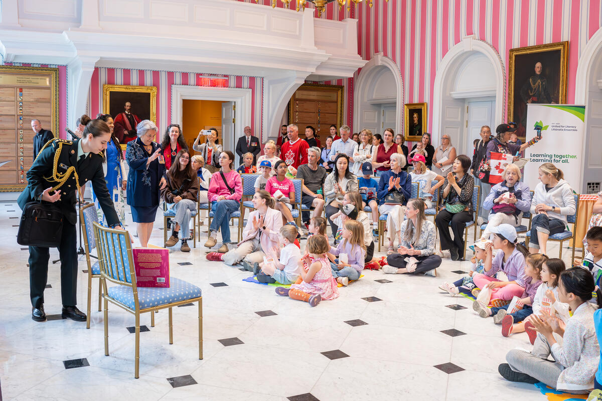 Governor General Mary Simon waving to a room of young children sitting on the floor.