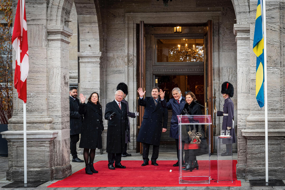 Row of people waving, including Their Majesties King Carl XVI Gustaf and Queen Silvia of Sweden.