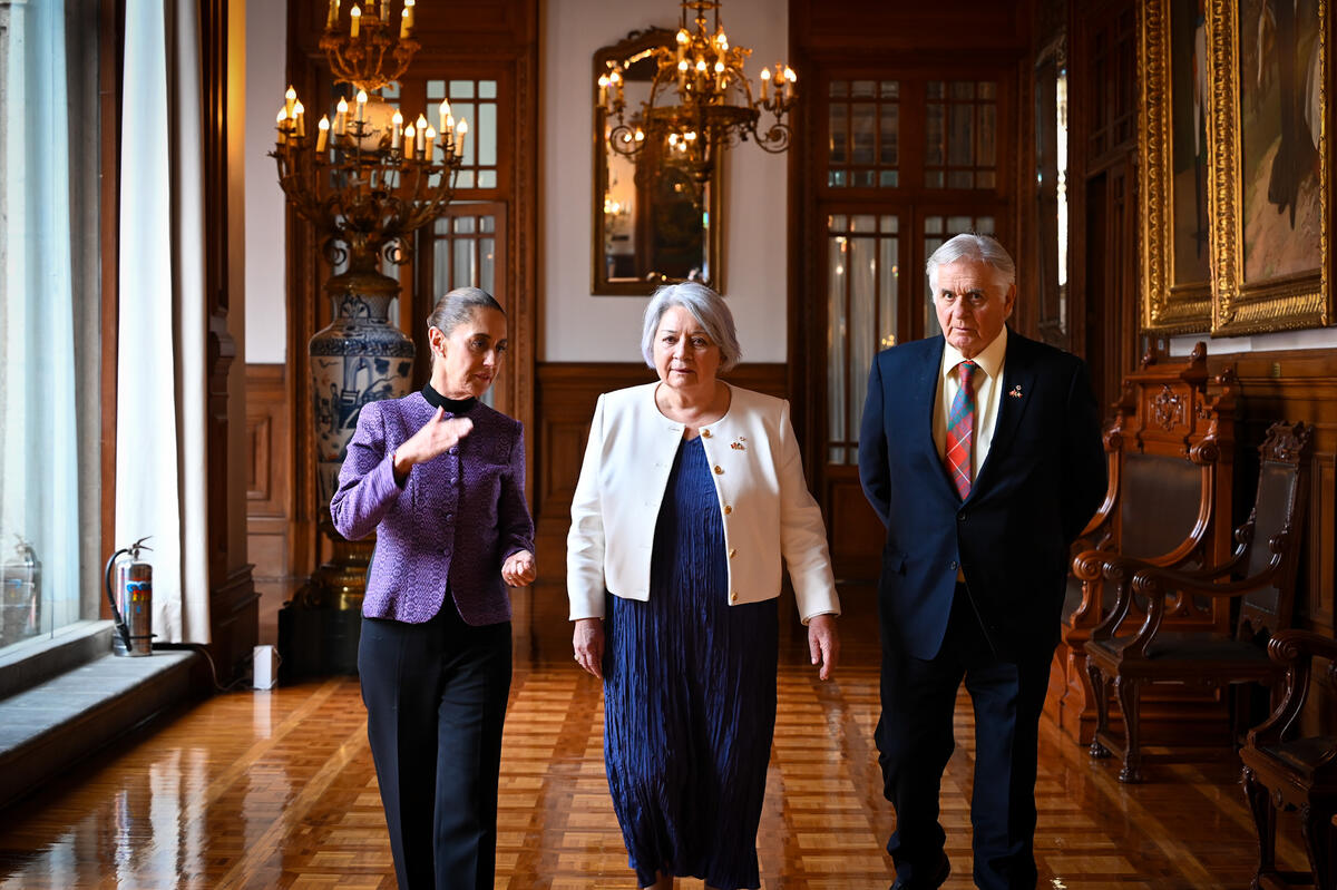 Left to right: Her Excellency Claudia Sheinbaum Pardo, President of the United Mexican States, Governor General Mary Simon and Mr. Whit Fraser walking down a corridor.